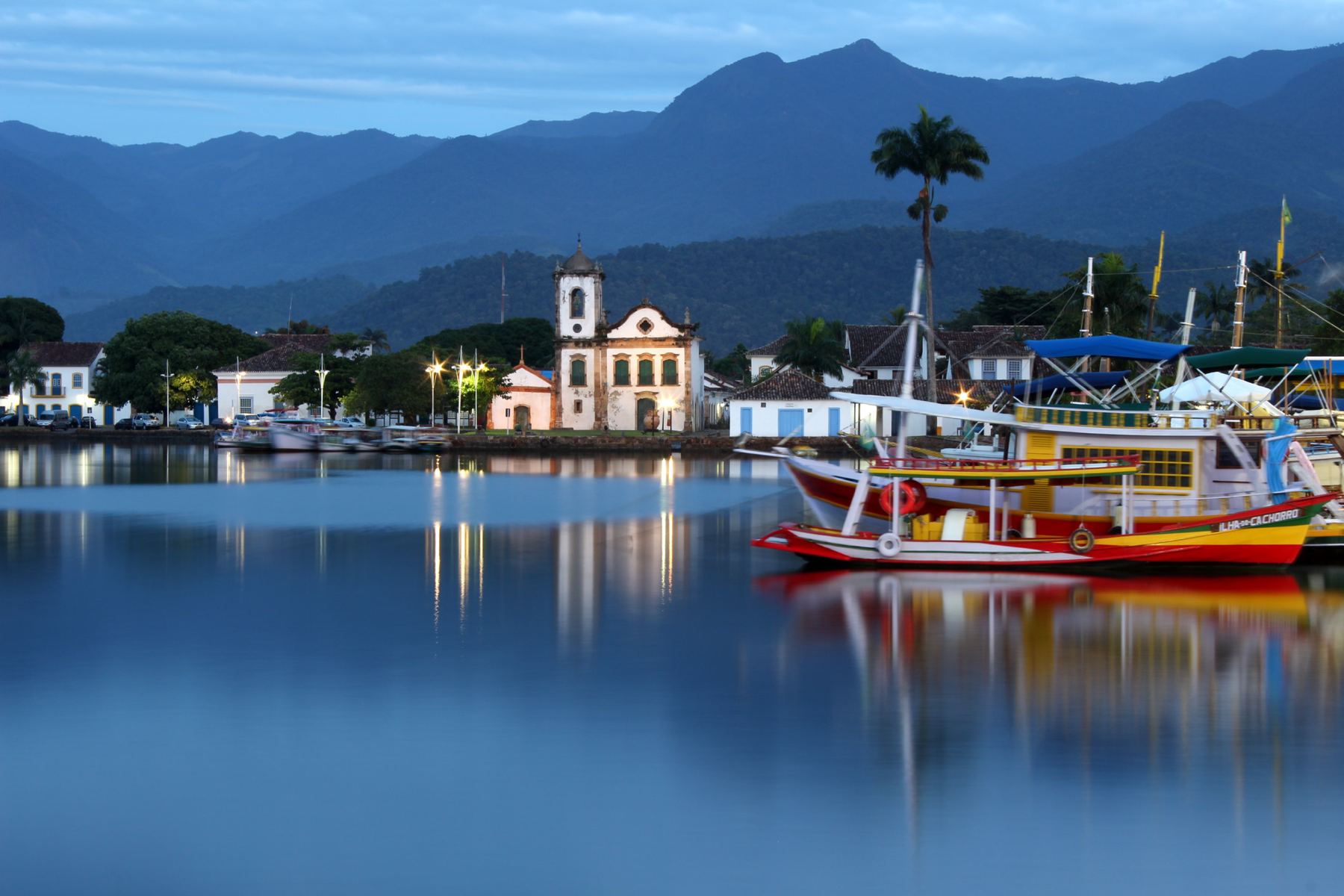 Centro Histórico de Paraty refletido na água, com a igreja e os barcos