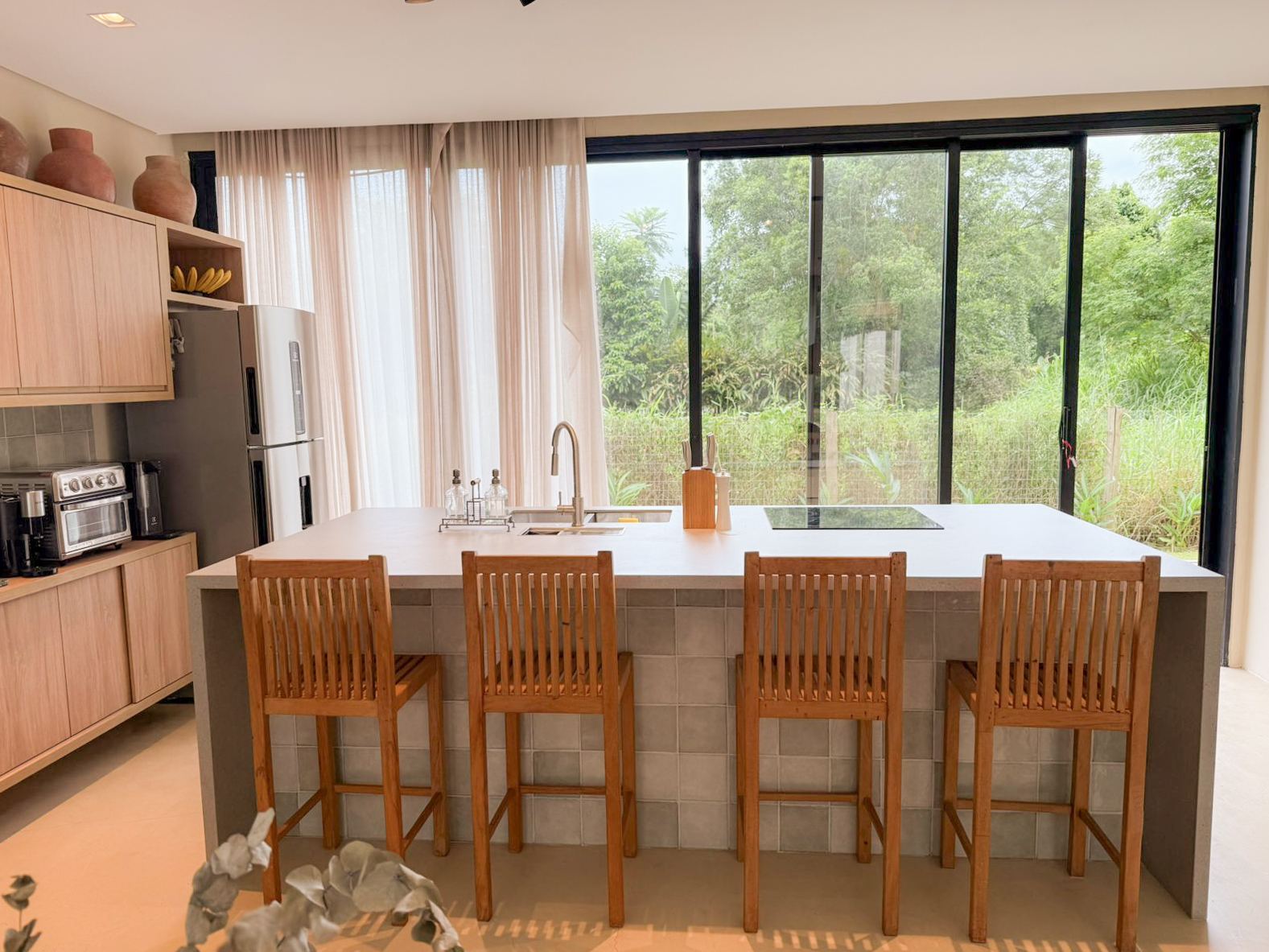 Ilha da cozinha com banquetas e vista para a mata