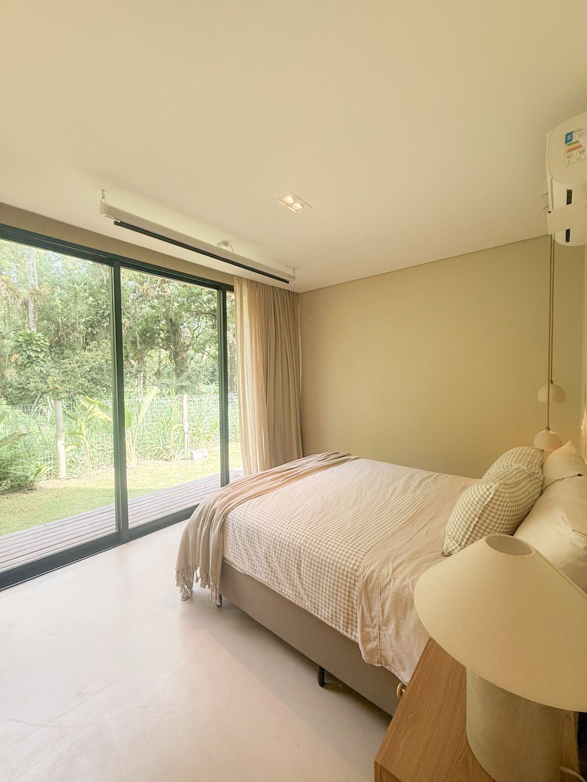 Cama da suíte master e porta de vidro para o jardim